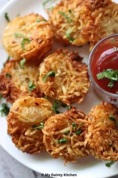 some fried food on a white plate with ketchup and dipping sauce in the middle