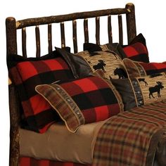 a bed with red and black plaid pillows on top of it next to a wooden headboard