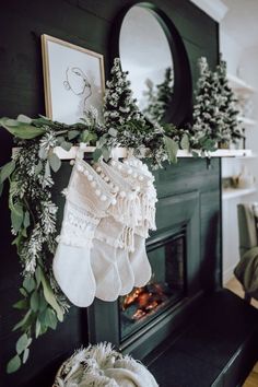 stockings hanging from the mantle in front of a fire place with greenery and wreaths