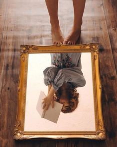 a person standing in front of a mirror with their feet on the floor and holding a piece of paper