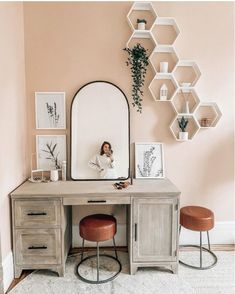 a desk with a mirror, stools and shelves on the wall in front of it