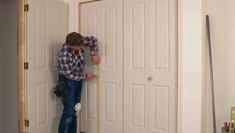 a man measuring the length of a door with a tape measure in front of him