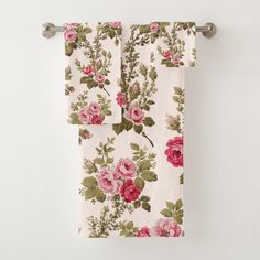 two towels hanging on the wall with pink roses and green leaves printed on them in front of a white background