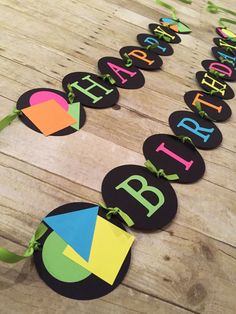 a wooden table topped with lots of paper cut out letters and ribbons that spell happy birthday