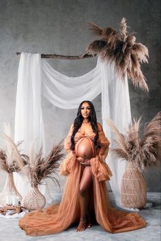 a pregnant woman posing for a photo in an orange gown with feathers around her waist