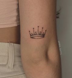 a woman's arm with a small crown tattoo on the left side of her arm