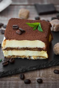 a piece of cake sitting on top of a black slate plate next to coffee beans