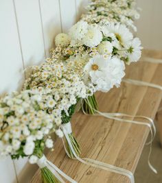 some white flowers are sitting on a wooden table and tied together with ribbon around them