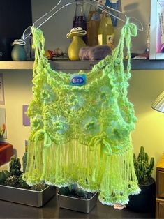 a neon green top hanging on a rack in front of some succulents