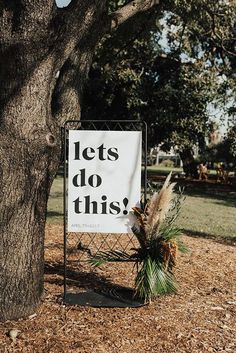 a sign that says let's do this next to a tree