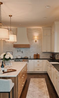 a large kitchen with white cabinets and wooden flooring, along with an area rug in the middle