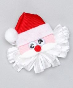 a red and white santa claus hat on top of a gray surface, with eyes wide open