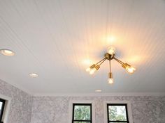 a room with three windows and two lamps on the ceiling, all in white marble