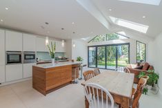 an open kitchen and dining room area with skylights on the ceiling, windows to outside