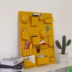 a yellow shelf with various items on it and a cactus in the corner next to it