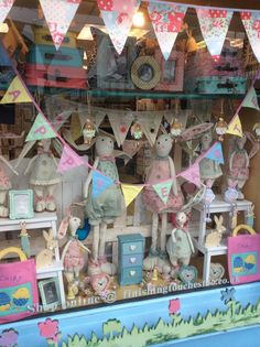 there are many stuffed animals on display in the store front window with flags and bunting