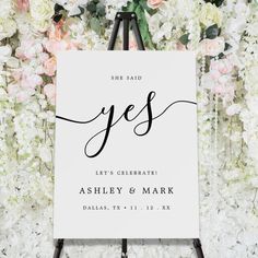 a white sign with the word yes written on it in front of some pink and white flowers