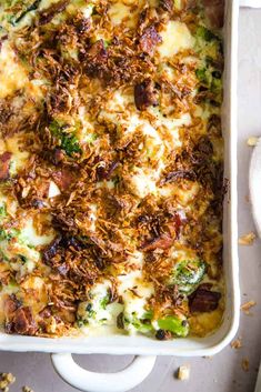 a casserole dish with broccoli, cheese and other toppings in it