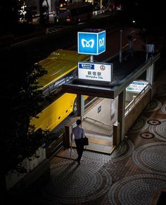 a man is walking up the stairs to an underground train station at night with signs above him