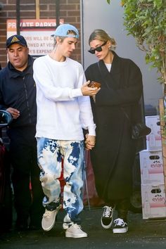 two people standing next to each other with one holding a doughnut in his hand