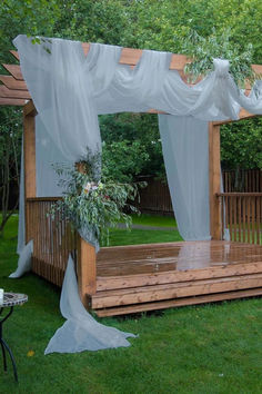 a wooden bench sitting in the middle of a lush green field next to a gazebo