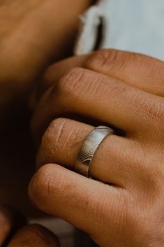 a close up of a person's hand with a wedding ring on their finger