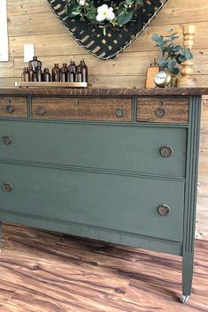 an old dresser is painted green and has flowers on top