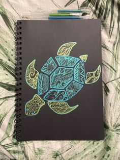 a notebook with an image of a sea turtle on it's cover, sitting on a bed