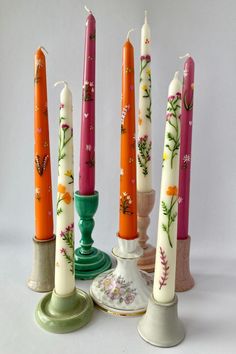 seven candles are lined up in different colors and designs, with one candle on top of the other