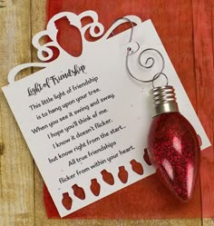 a card with a message attached to it and a red light bulb hanging from the back