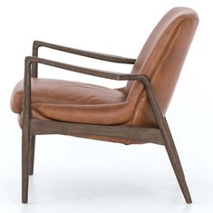 a brown leather chair sitting on top of a white floor next to a wooden frame