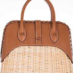 This Hermes Picnic Bolide, crafted in 2017, is an exquisite blend of rustic charm and refined elegance. This unique bag marries the natural beauty of Osier Wicker with the luxurious touch of Fauve Barenia leather, creating an accessory that is both visually stunning and tactilely inviting. The body of the bag is made from finely woven Osier Wicker, evoking the essence of serene summer days and elegant countryside escapades. This natural material adds an element of artisanal craftsmanship and giv Luxury Straw Bag With Woven Leather Basket, Luxury Brown Basket Straw Bag, Designer Natural Straw Bag With Bamboo Handle, Luxury Straw Basket Bag With Detachable Handle, Luxury Basket Straw Bag With Detachable Handle, Elegant Leather Straw Bag With Detachable Handle, Luxury Basket Bag With Bamboo Handle, Elegant Natural Woven Leather Bag, Luxury Top Handle Straw Bag With Woven Leather