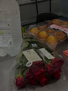 flowers, donuts and bottled water are on the counter in front of some plastic bags