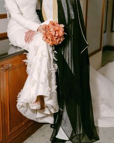 the bride and groom are sitting together in their wedding day attire, holding each other's bouquet