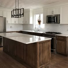 a large kitchen with an island in the middle and stainless steel appliances on both sides