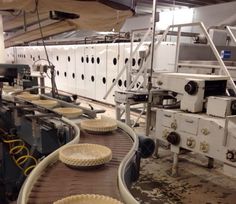 several pies are lined up on a conveyor belt