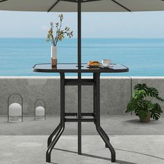 an umbrella and table with flowers on it overlooking the ocean