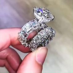 a person is holding an engagement ring with two diamonds on it's sides and the other side