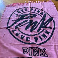 a pink towel with black ink on it sitting on top of a wooden floor next to a table