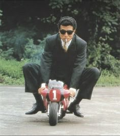 a man riding on the back of a red motorcycle