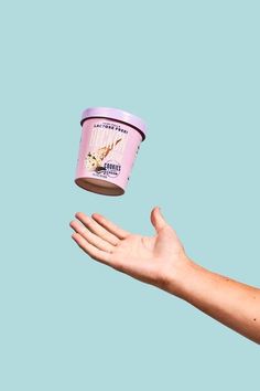 a person holding out their hand with a pink ice cream container in it's palm