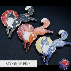 three pin badges with different designs and colors on black background, one has an image of a cat and the other is a fox