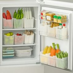 an open refrigerator filled with lots of food and containers on the door, including carrots, celery, corn, broccoli