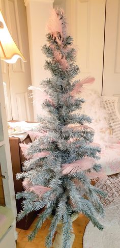 a small blue christmas tree sitting on top of a wooden floor next to a bed