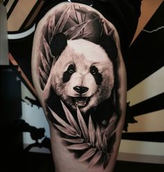 black and white tattoo of a panda bear with leaves on it's back leg