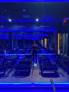 a woman taking a selfie in front of a blue lit room with rows of chairs