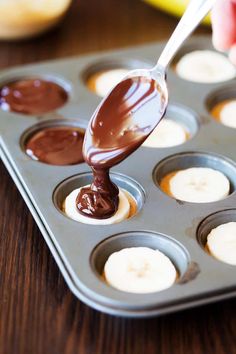 someone is dipping chocolate into banana slices in a muffin tin