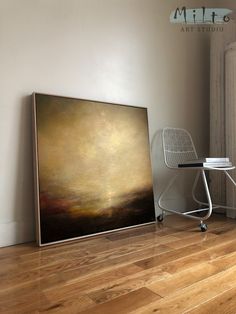 a painting sitting on top of a hard wood floor next to a chair and table