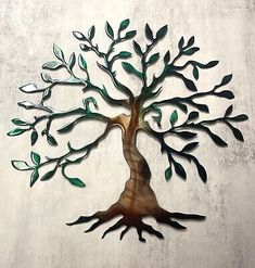 a metal tree with green leaves on it's branches is shown against a white wall