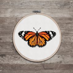 a cross stitch butterfly sitting on top of a wooden table